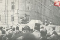 Sovietsky dôstojník mieriaci na demonštrantov pištoľou z obrneného transportéra.