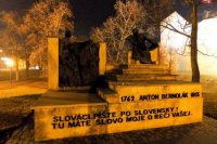 Známy pamätník Antona Bernoláka, v pozadí vysvietený park a hradby
