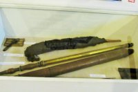 V strede fotografie je mosadzná vodná puška. Vedľa nej je celodrevená vodná puška. Hore je fakľa.