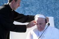 tlmočník dáva sluchadlá pápežovi Františkovi počas jeho stretnutia s predstaviteľmi štátu, občianskej spoločnosti a diplomatického zboru