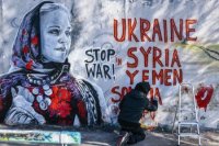 Kolumbíjsky pouličný umelec žijúci v Berlíne Arte Vilu maľuje na stenu obraz ukrajinskej ženy v tradičnom odeve v Berlíne.